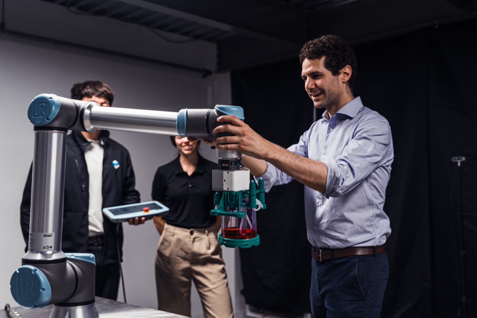 The Multiply Labs team adjusting a robotic arm holding laboratory equipment